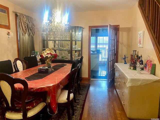 dining space featuring dark hardwood / wood-style flooring, an inviting chandelier, and a wall unit AC