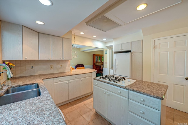 kitchen featuring tasteful backsplash, white appliances, sink, a center island, and light tile patterned flooring