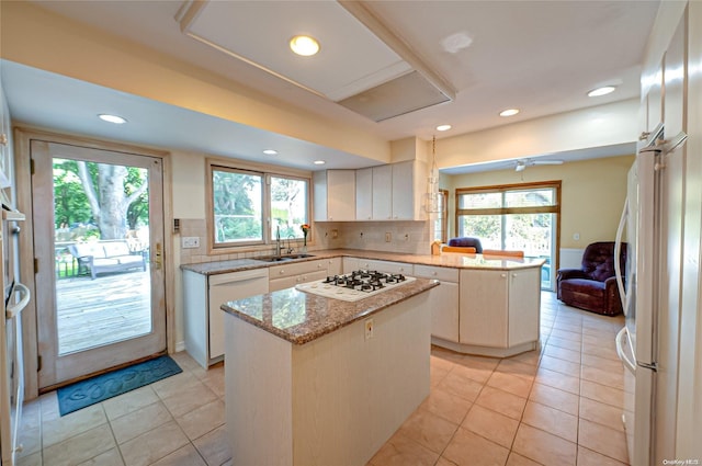 kitchen featuring a kitchen island, white appliances, backsplash, and white cabinetry