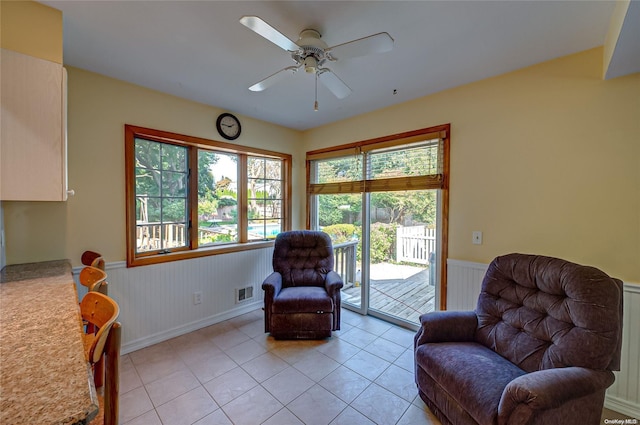 living area with light tile patterned floors and ceiling fan