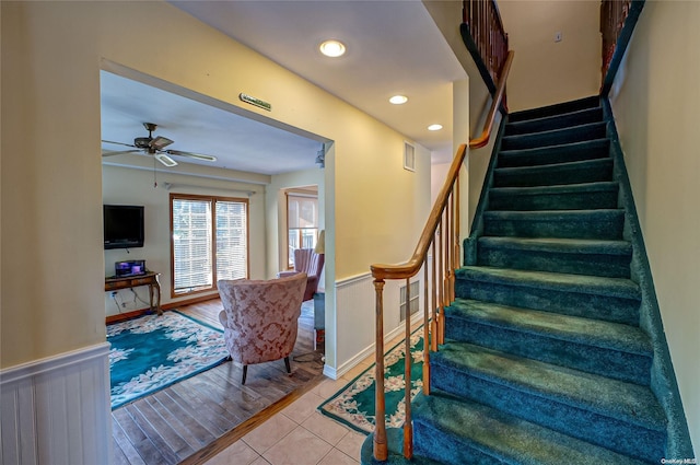 stairway with hardwood / wood-style flooring and ceiling fan