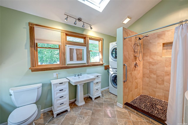 bathroom with vaulted ceiling with skylight, stacked washer / drying machine, walk in shower, and a wealth of natural light