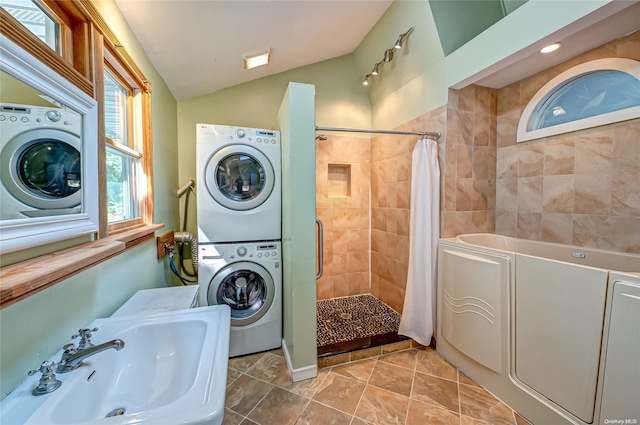 laundry room featuring light tile patterned floors, stacked washer and dryer, and sink