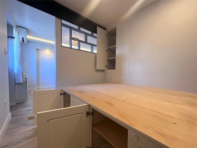 unfurnished office featuring light wood-type flooring and an AC wall unit