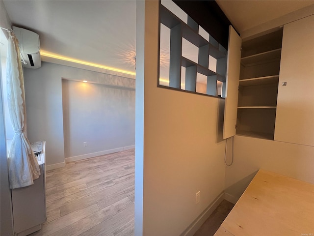 hallway with a wall unit AC and hardwood / wood-style floors