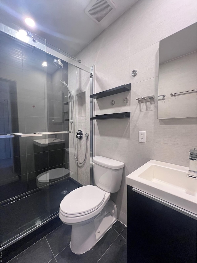 bathroom with tile patterned floors, vanity, toilet, and a shower with shower door