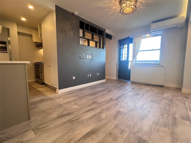 empty room with a chandelier, light hardwood / wood-style floors, and a wall mounted AC