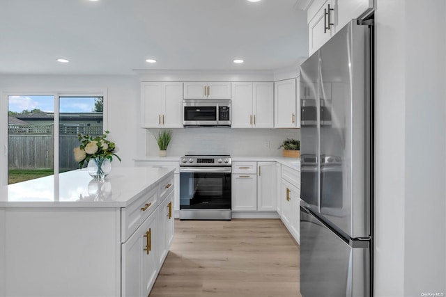 kitchen with a center island, white cabinets, decorative backsplash, light wood-type flooring, and appliances with stainless steel finishes