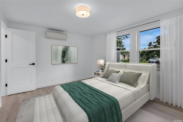 bedroom with light hardwood / wood-style floors and a wall unit AC