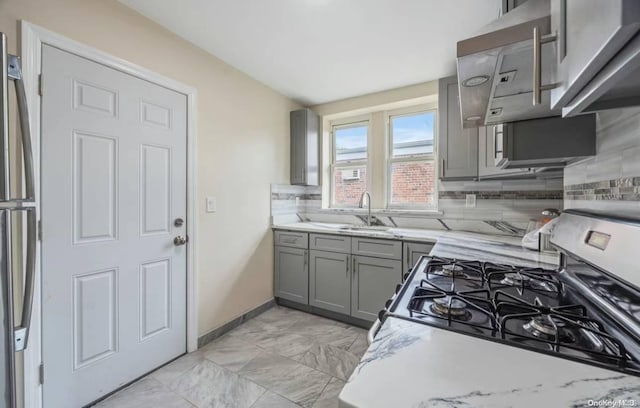 kitchen with gray cabinetry, decorative backsplash, sink, and appliances with stainless steel finishes