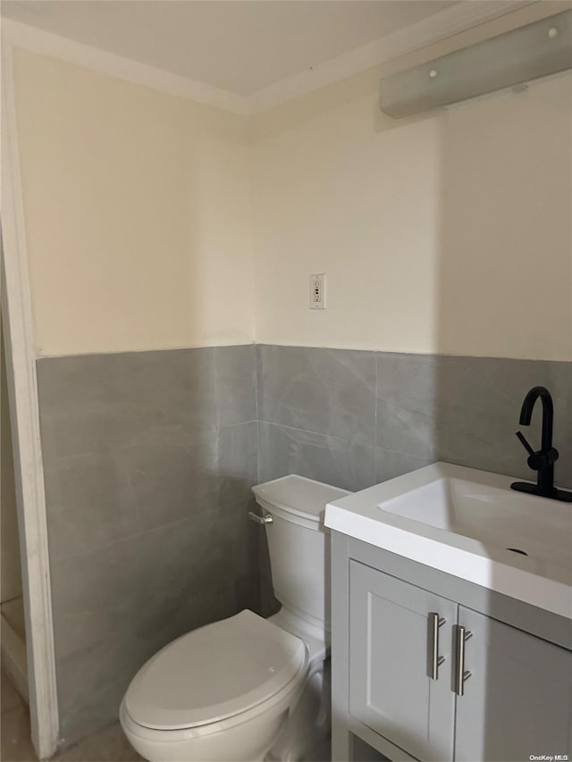 bathroom with vanity, toilet, and tile walls