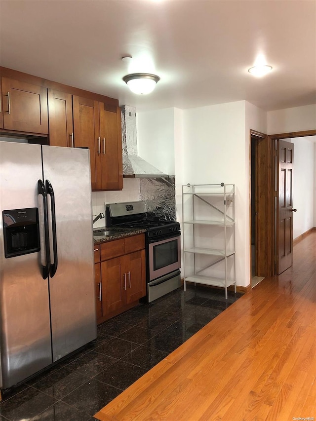 kitchen featuring backsplash, dark stone counters, ventilation hood, dark hardwood / wood-style floors, and appliances with stainless steel finishes