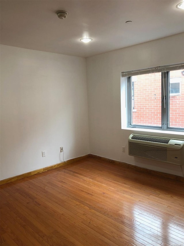 unfurnished room with light wood-type flooring and a wall unit AC