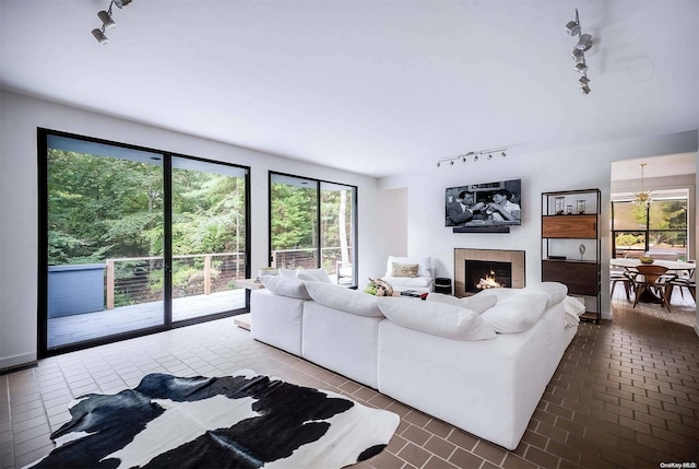 living room featuring track lighting, a notable chandelier, and a tiled fireplace