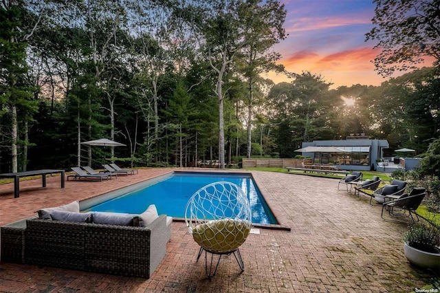 pool at dusk with a patio area