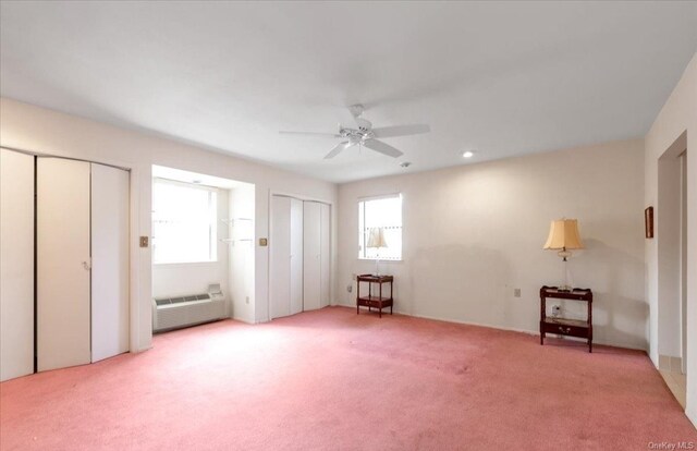 interior space featuring light carpet, ceiling fan, and multiple closets