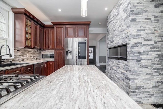 26-44 211th St, Bayside, NY 11360 - kitchen featuring appliances with stainless steel finishes, a sink, glass insert cabinets, decorative backsplash, and reddish brown cabinets