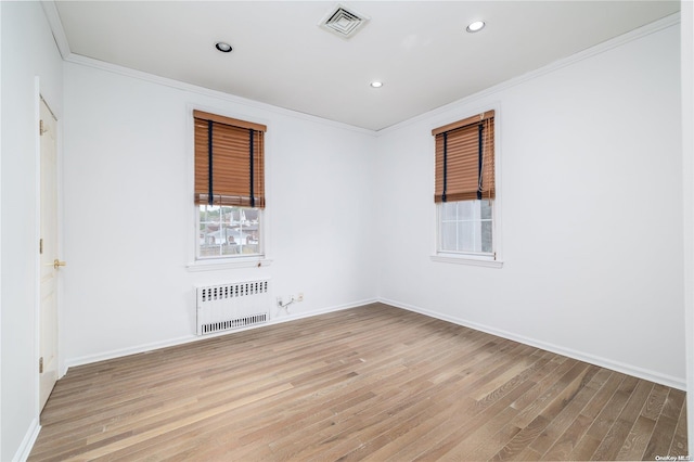 spare room featuring light hardwood / wood-style floors, radiator heating unit, and crown molding