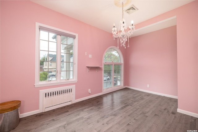 unfurnished dining area with a wealth of natural light, wood-type flooring, and radiator