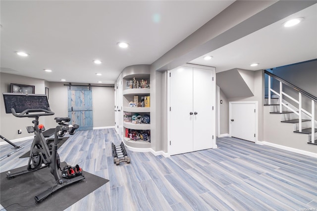 exercise area with a barn door and hardwood / wood-style flooring