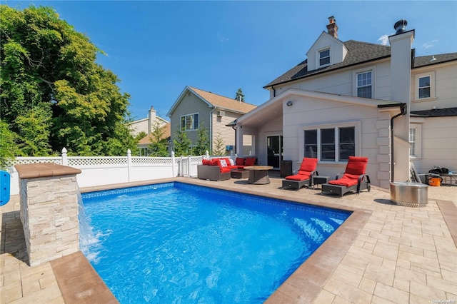 rear view of house with an outdoor living space, a patio area, and a fenced in pool