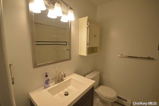 bathroom featuring vanity, toilet, and a baseboard heating unit