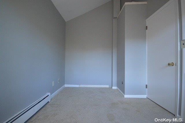 carpeted spare room with baseboard heating and lofted ceiling