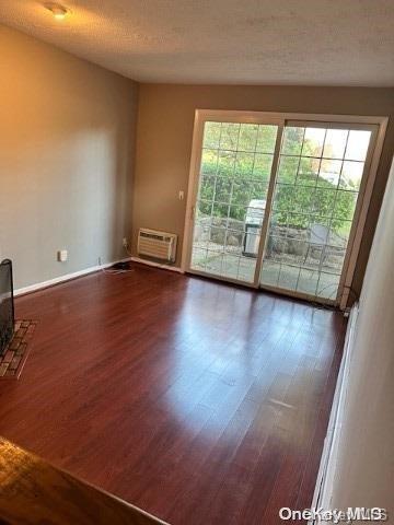 interior space featuring dark hardwood / wood-style flooring, a textured ceiling, and a wall unit AC