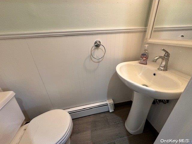 bathroom with hardwood / wood-style flooring, toilet, and baseboard heating