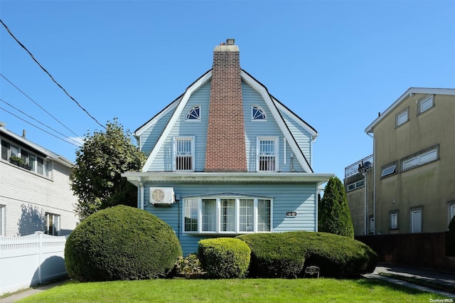 exterior space featuring a lawn and a wall mounted AC