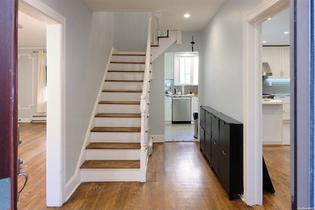 staircase with hardwood / wood-style floors and a baseboard heating unit