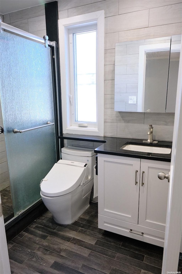 bathroom with a wealth of natural light, vanity, a shower with shower door, and hardwood / wood-style flooring