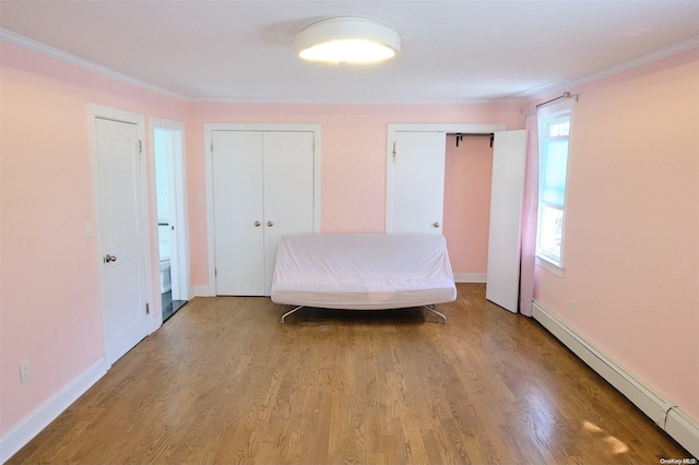 unfurnished bedroom featuring multiple closets, crown molding, a baseboard radiator, and light hardwood / wood-style floors