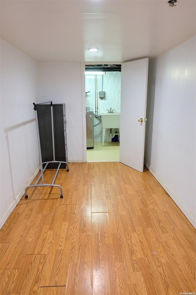 unfurnished room with sink, light hardwood / wood-style floors, and washer / dryer