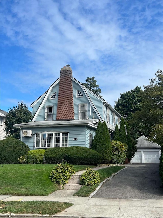 view of side of home featuring a lawn, a garage, and an outbuilding