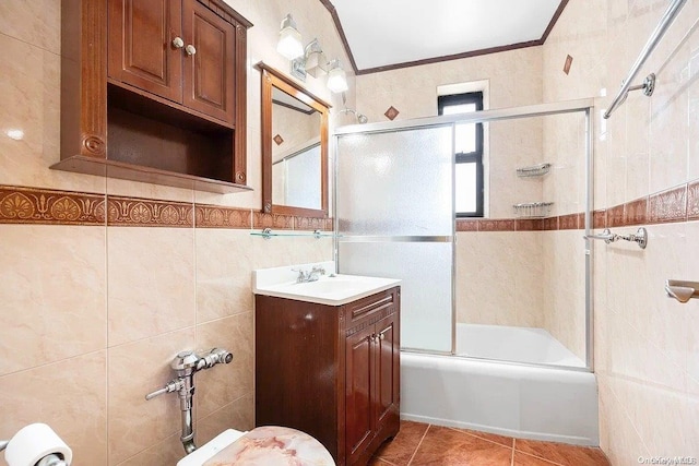 bathroom featuring tile patterned floors, crown molding, combined bath / shower with glass door, vanity, and tile walls