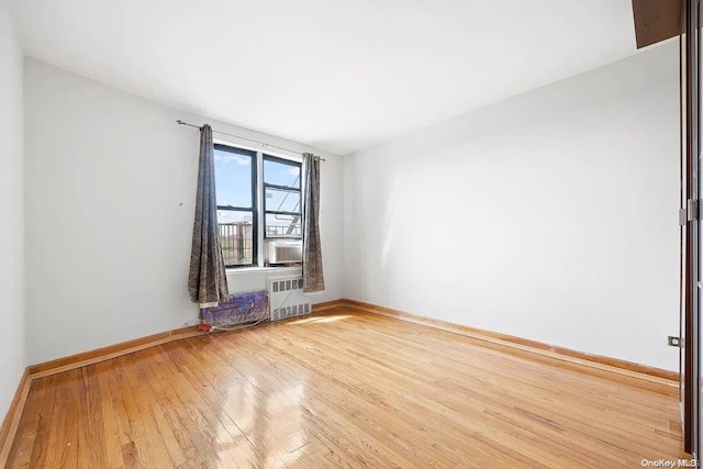 spare room with hardwood / wood-style floors, radiator, and cooling unit