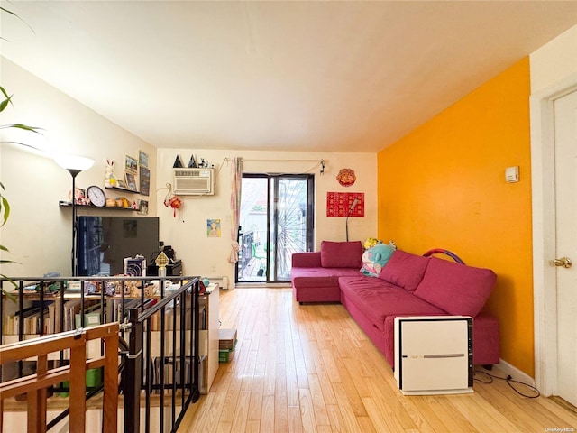 living room featuring an AC wall unit and light hardwood / wood-style floors