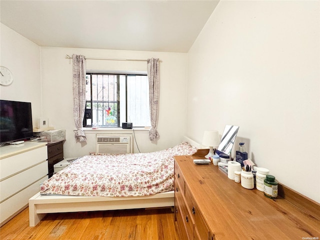 bedroom with light hardwood / wood-style floors and a wall unit AC