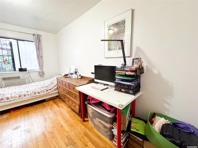 bedroom with a wall unit AC and light hardwood / wood-style floors