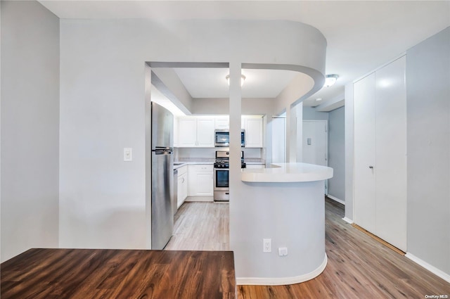 kitchen featuring kitchen peninsula, light wood-type flooring, white cabinetry, and stainless steel appliances