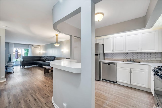 kitchen featuring tasteful backsplash, stainless steel appliances, pendant lighting, light hardwood / wood-style flooring, and white cabinets