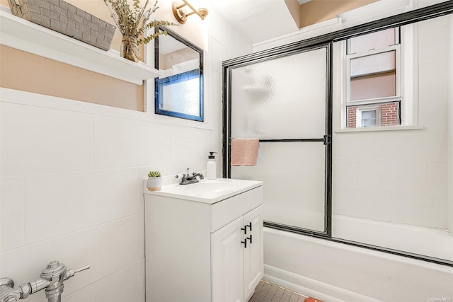 bathroom with vanity, tile walls, a healthy amount of sunlight, and enclosed tub / shower combo