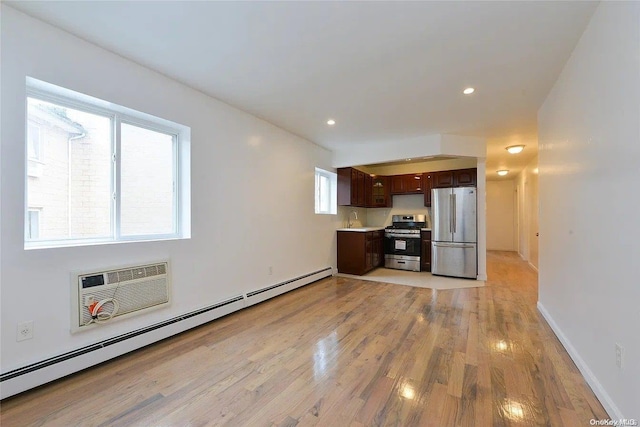 kitchen featuring a wall mounted air conditioner, light wood-type flooring, dark brown cabinets, stainless steel appliances, and a baseboard radiator