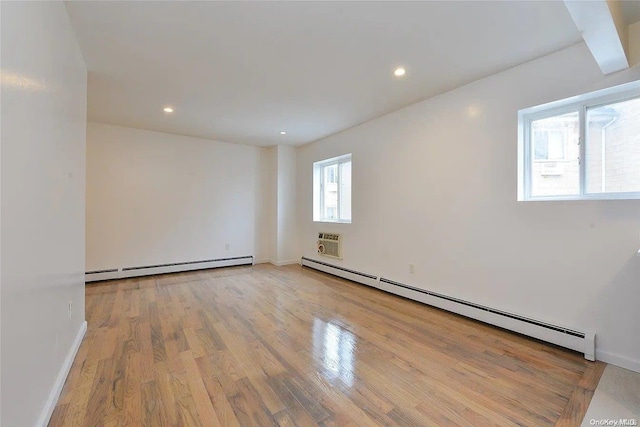 empty room with a baseboard radiator, a wall mounted AC, and light hardwood / wood-style floors