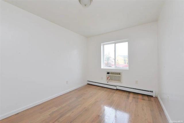 unfurnished room featuring baseboard heating, light hardwood / wood-style floors, and a wall mounted air conditioner