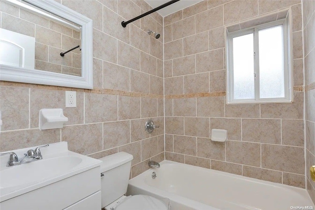 full bathroom with tiled shower / bath, vanity, tile walls, and toilet