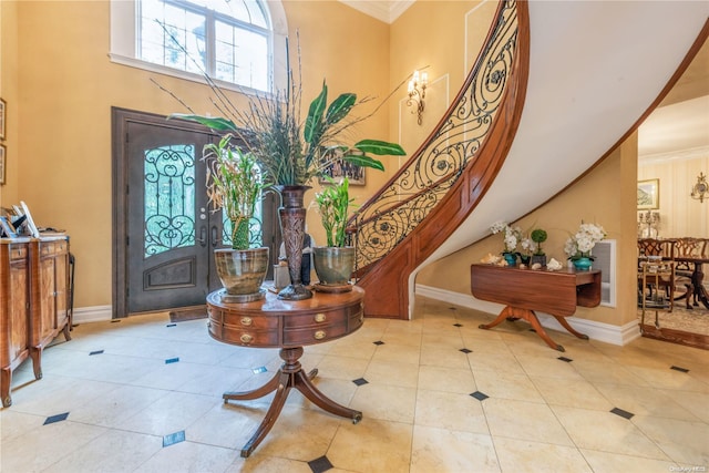 foyer featuring french doors, a towering ceiling, light tile patterned floors, and ornamental molding