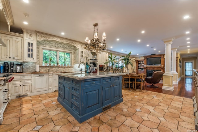 kitchen with decorative backsplash, sink, hanging light fixtures, and a kitchen island with sink