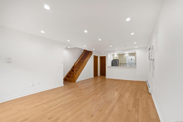 unfurnished living room with light hardwood / wood-style flooring and a baseboard heating unit